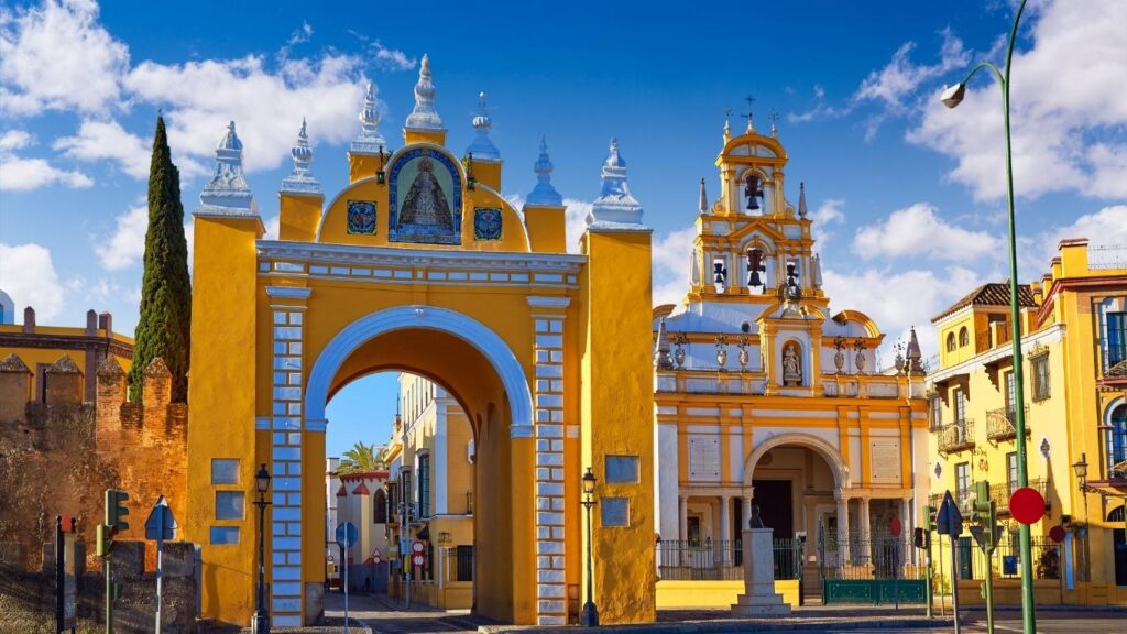Arco amarillo de la Puerta de la Macarena y la Basílica de la Macarena al fondo, formando parte de la antigua muralla de Sevilla.