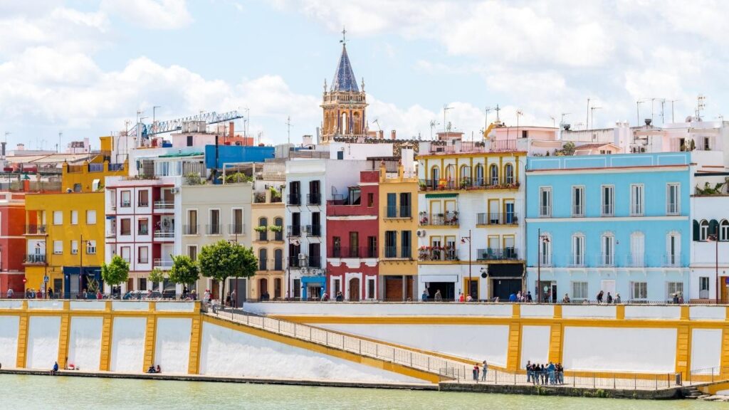 Casas de colores a lo largo de la Calle Betis en Triana, reflejándose en el río Guadalquivir al atardecer en Sevilla.