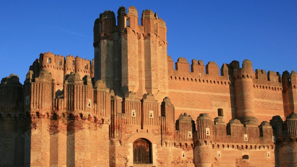 Imponente fachada y torres de ladrillo rojo del Castillo de Coca en Segovia, el máximo exponente del mudéjar militar.