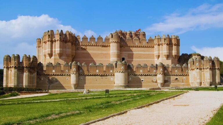Vista panorámica del Castillo de Coca en Segovia, destacando sus fosos y el contraste de su arquitectura de ladrillo con el entorno.