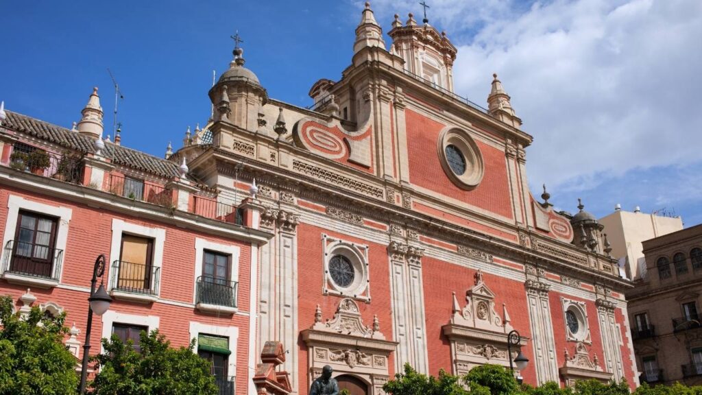 Fachada principal de la Iglesia Colegial del Divino Salvador en Sevilla, de ladrillo rojizo y detalles barrocos.