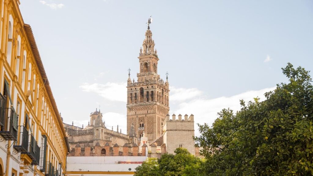 Vista en primer plano de la torre campanario de La Giralda, antiguo minarete almohade de la Catedral de Sevilla, bajo un cielo claro.