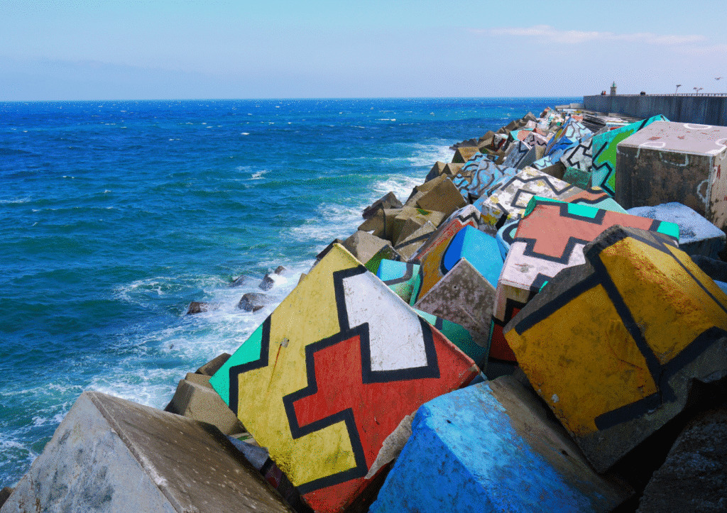 Los Cubos de la Memoria en el puerto de Llanes, coloridas obras de arte sobre los bloques del espigón con vistas al mar Cantábrico en Asturias.