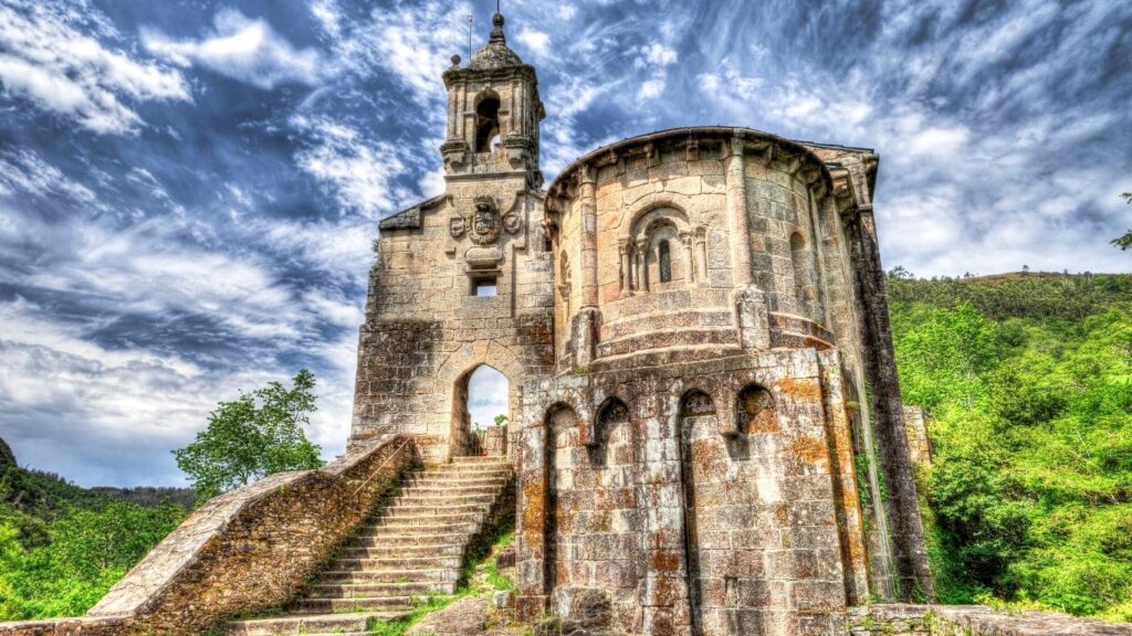 Ruinas de la iglesia románica del Monasterio de San Juan de Caaveiro en A Coruña, un enclave místico en la Ruta del Románico gallego rodeado de vegetación.