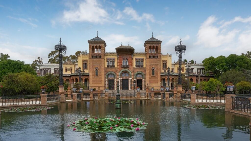 El estanque y el Pabellón Mudéjar (actual Museo de Artes y Costumbres Populares) en el Parque de María Luisa, con nenúfares en el agua.