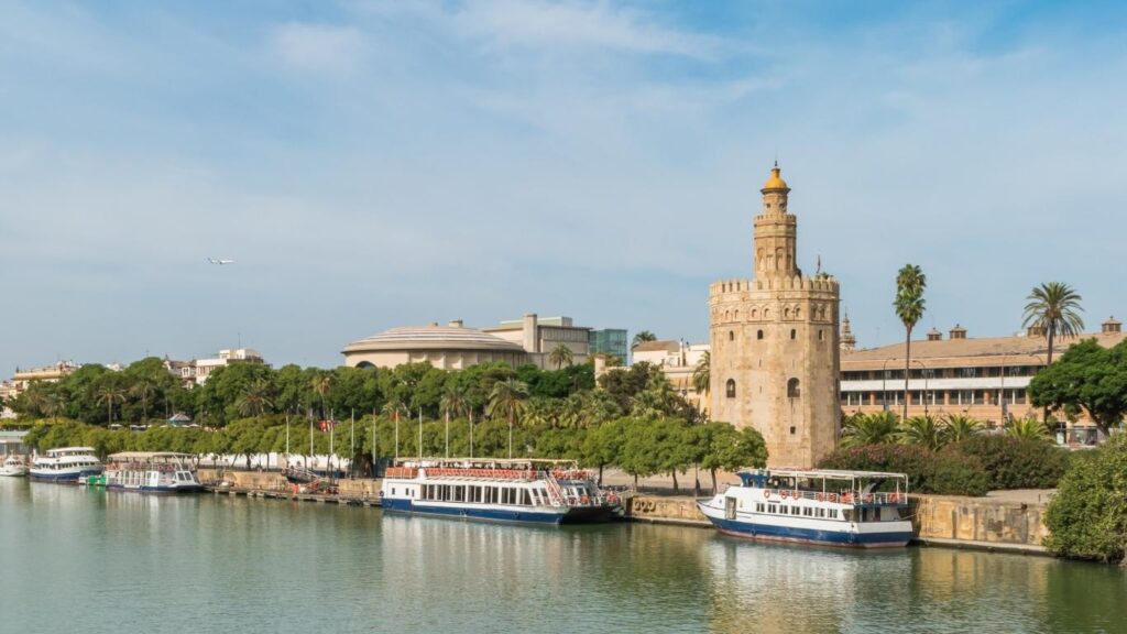 La Torre del Oro, una torre albarrana dodecagonal, vista desde el río Guadalquivir con embarcaciones turísticas.