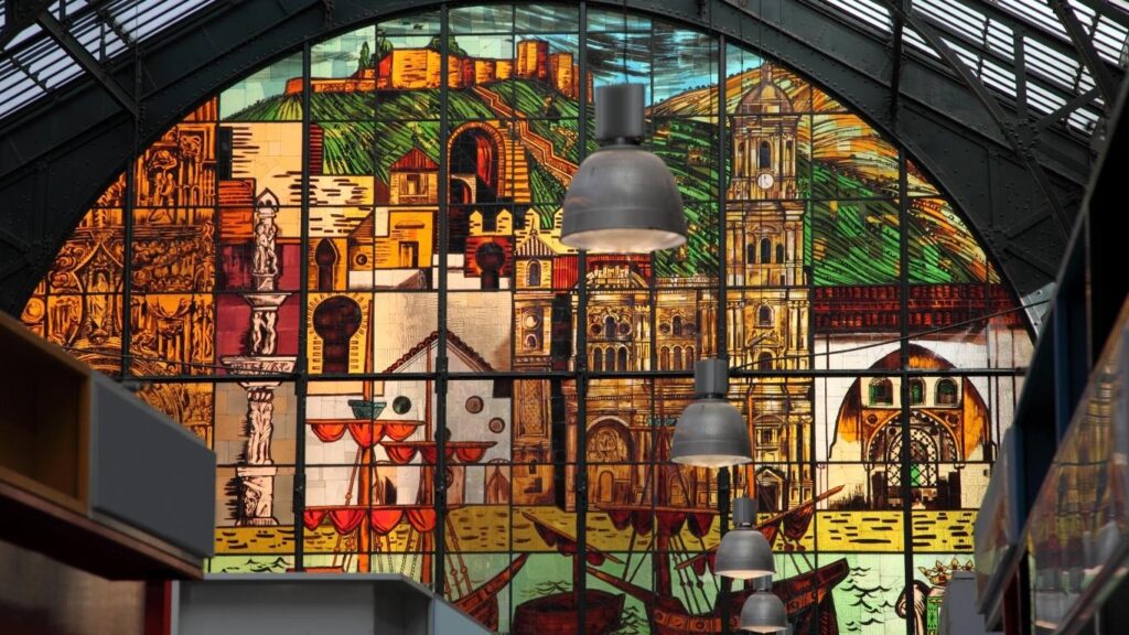 Vidriera de colores de la fachada del Mercado de Atarazanas que representa la historia de Málaga, incluyendo barcos, la Catedral y la Alcazaba.