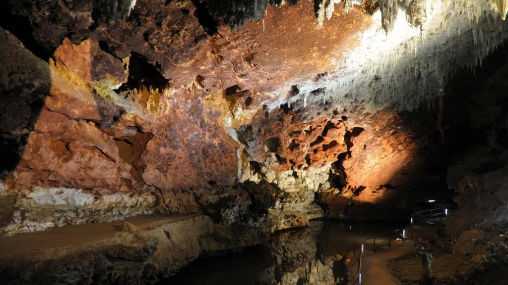 Interior de la Cueva El Soplao en Cantabria mostrando formaciones de estalactitas y estalagmitas con iluminación artificial.