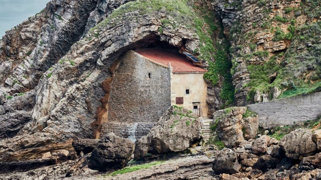 Primer plano de la Ermita de Santa Justa construida dentro de una cavidad natural en el acantilado rocoso de Ubiarco, Cantabria.