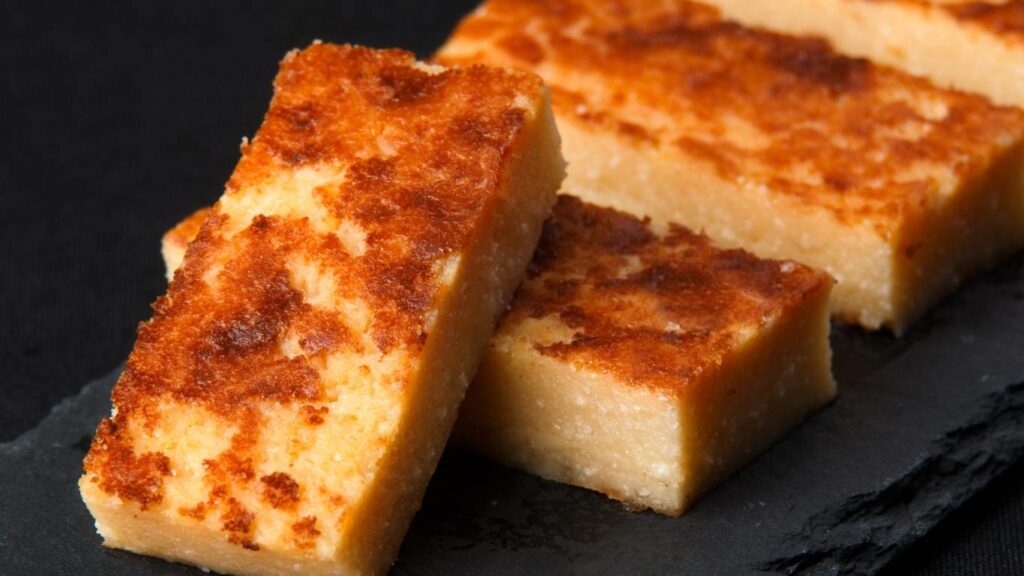 Porciones de quesada pasiega tradicional con su característica capa tostada servidas sobre una tabla de pizarra.