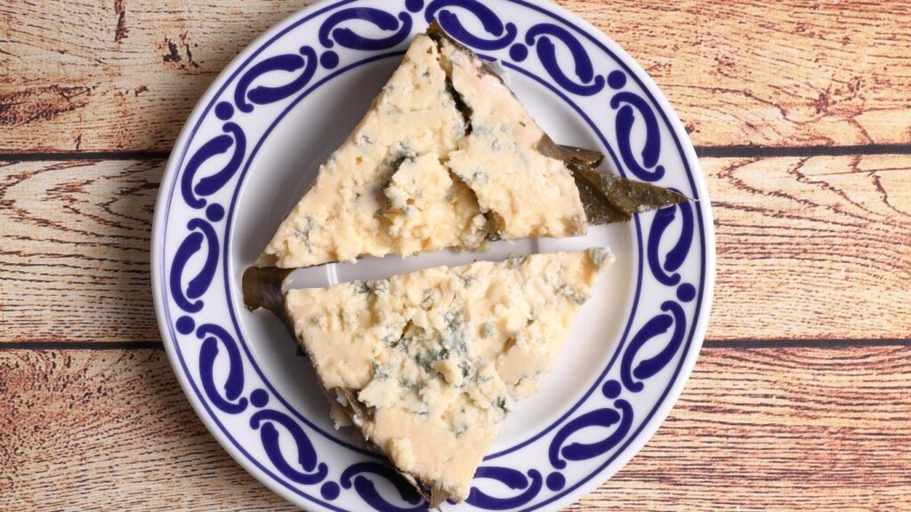 Dos trozos de queso picón azul sobre un plato blanco con borde azul, producto típico de la gastronomía de Cantabria.