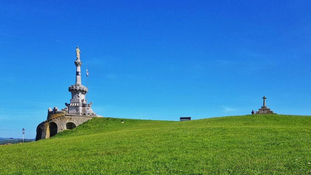 Monumento modernista al Marqués de Comillas ubicado en lo alto de una colina verde bajo un cielo despejado en Cantabria.