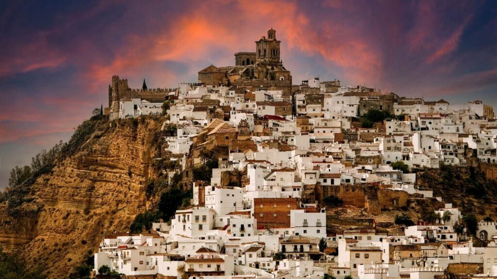 Panorámica de Arcos de la Frontera al atardecer, inicio de la Ruta por los Pueblos Blancos de Cádiz con su iglesia en lo alto del tajo.