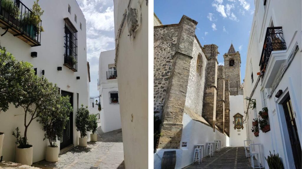 Calle Nuestra Señora de la Oliva en Vejer, mostrando la arquitectura de piedra de la iglesia y las fachadas blancas adyacentes.
