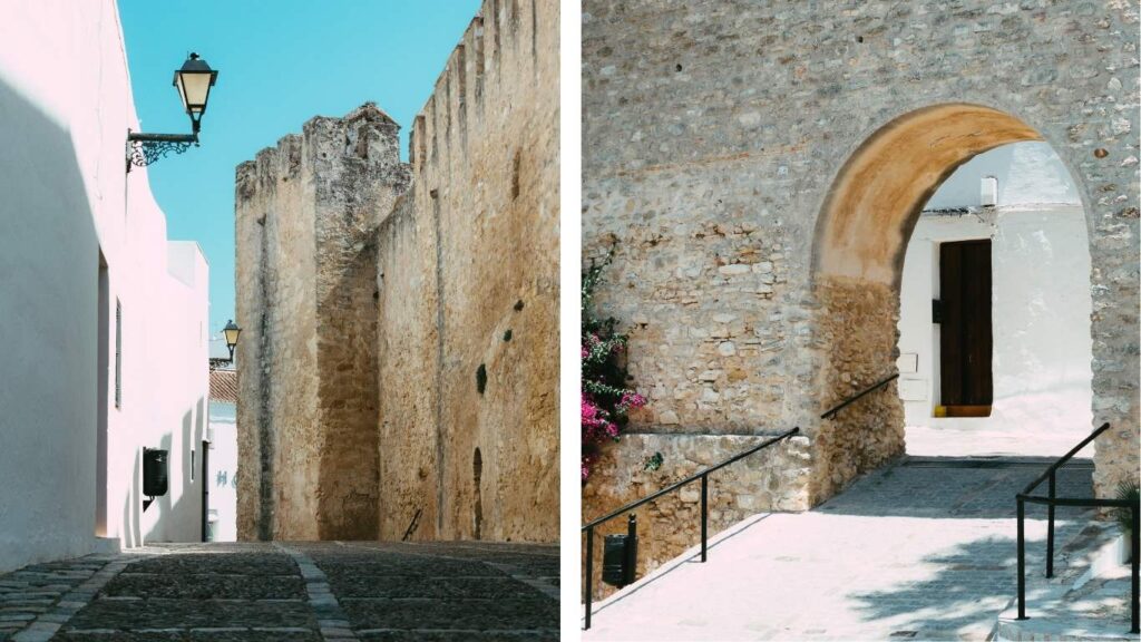 Murallas de piedra y arco de entrada del Castillo de Vejer de la Frontera bajo un cielo azul despejado.