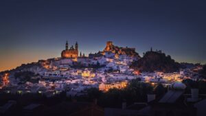 Panorámica de Arcos de la Frontera al atardecer, con la iglesia de Santa María de la Asunción en lo alto del tajo sobre las casas blancas.
